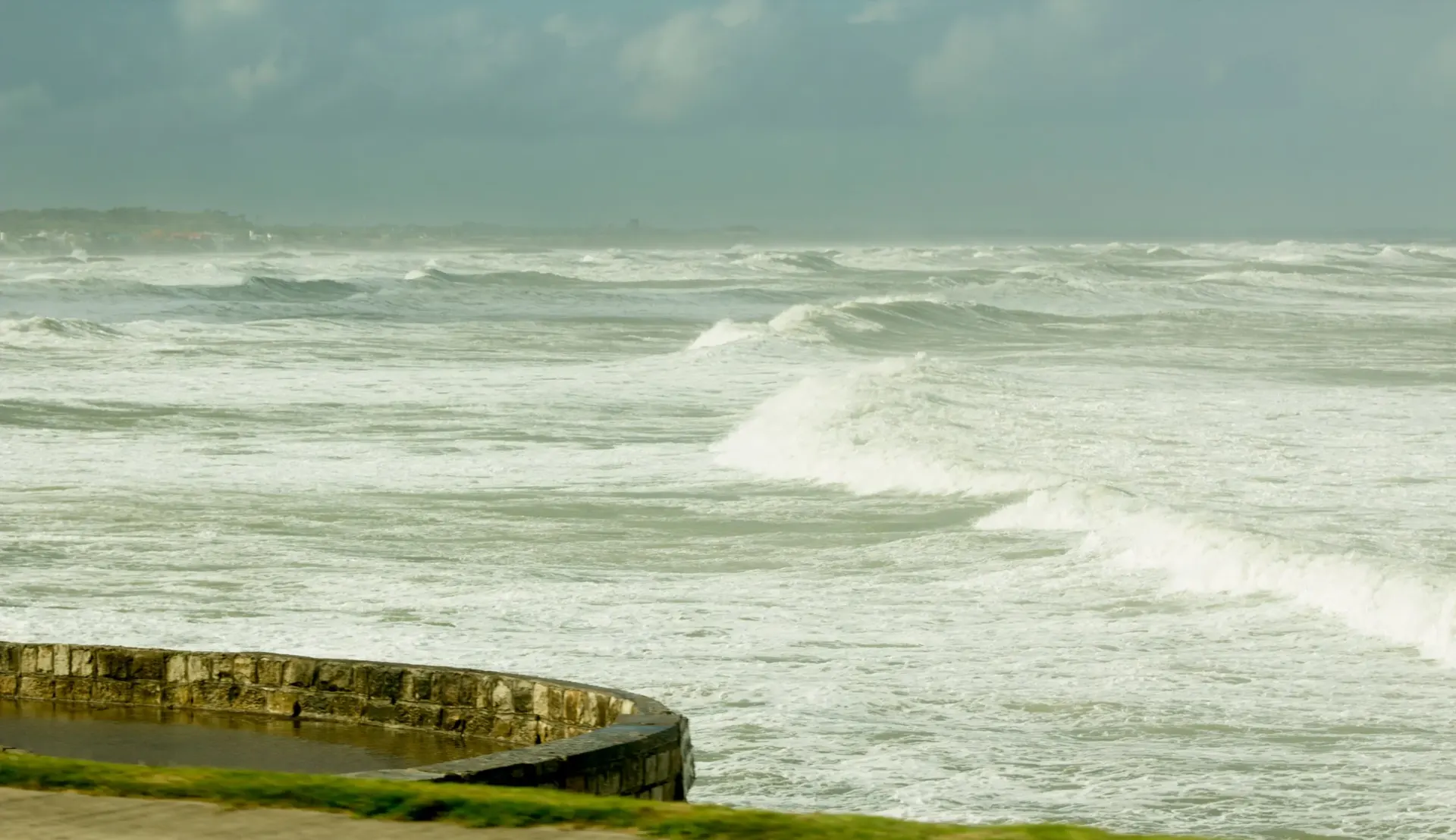 Mar revuelto con olas que rompen contra un murallón en la costa de Mar del Plata